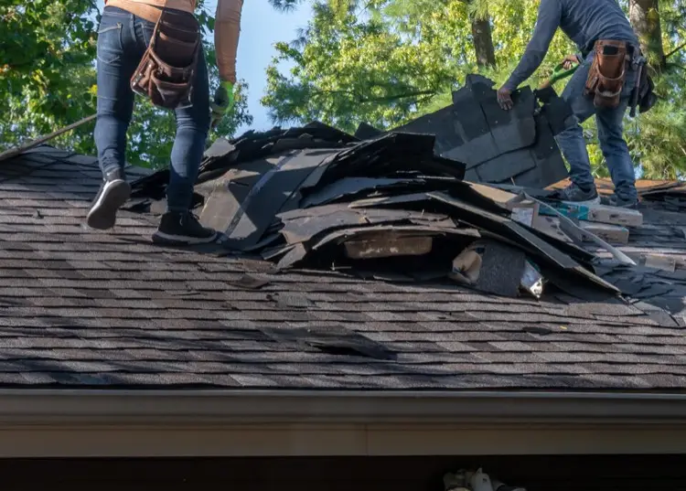 Team of roofers removing old roofing materials
